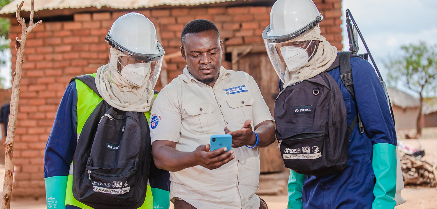 men in spraying gear talking to supervisor in african village