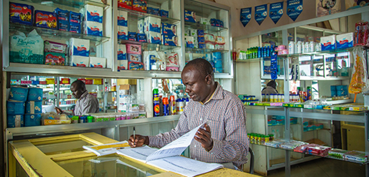 tanzanian pharmacist looking through papers in his pharmacy