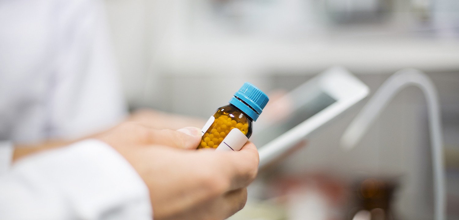 Scientist holding pill bottle and digital tablet