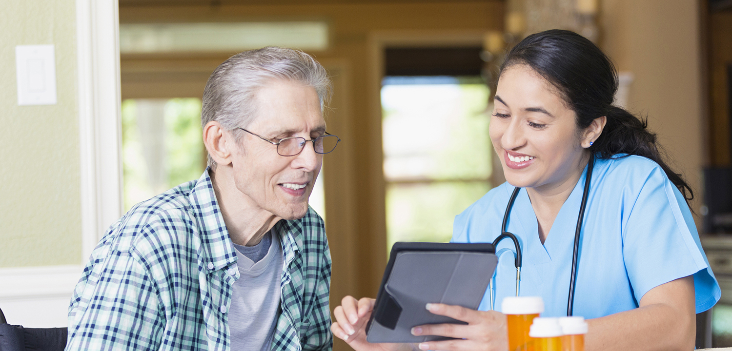 Nurse reviews senior patient's medical chart on digital tablet