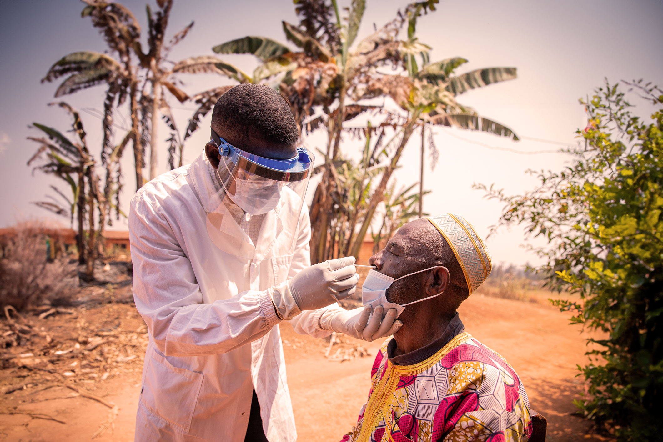 Man in Africa applying a nose swab to another man to test for an infectious disease