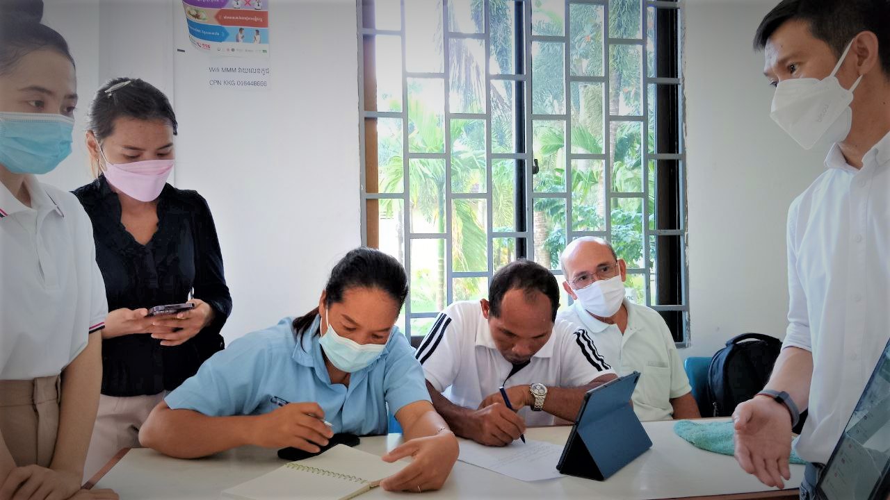 Cambodian men and women with medical masks around a table