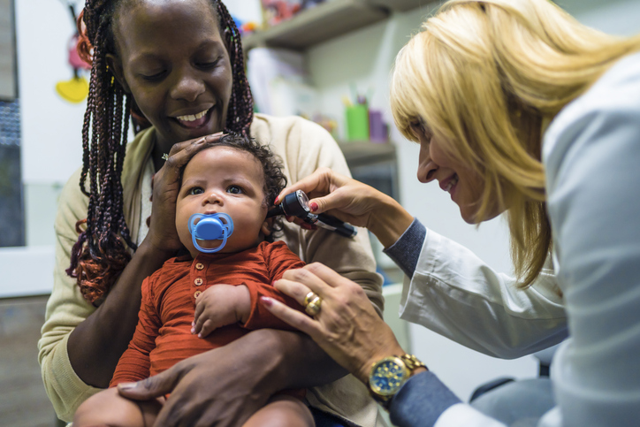 Doctor examining a baby with an otoscope