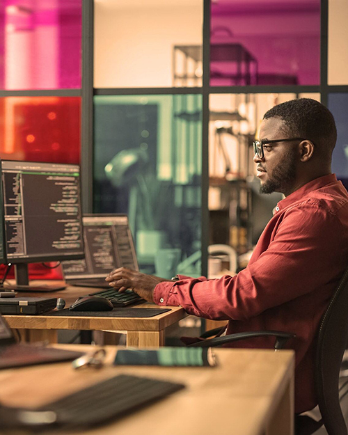 man working at a computer with multiple monitors