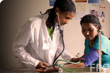 An African woman who is a medical professional takes the blood pressure of an African
