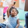 little girl with her hand raised in classroom